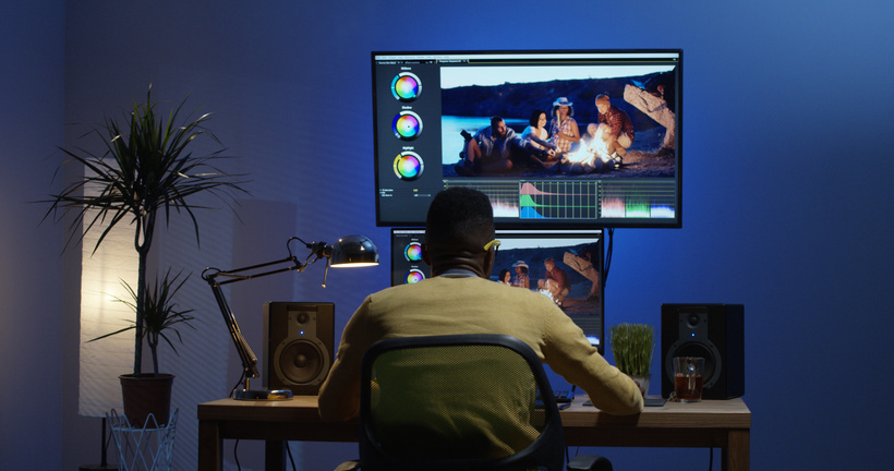 Young man sitting back and editing a video inside a room